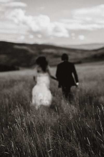 Blurry black and white shot of couple walking through a field during a Breckenridge elopement.