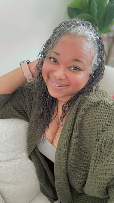 Letitia Hopkins smiling in an olive green sweater, embodying self-love, confidence, and Main Character Energy as a life, love, and relationship coach empowering women to create aligned lives and relationships.