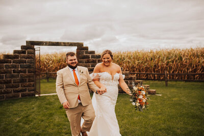 bride and groom walking in front of a brick wall at their Michigan barn wedding