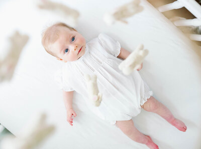A newborn baby lying in a crib, looking at the mobile during Fort Worth newborn photography session with Allison Krogness Photography.