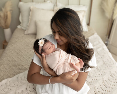 mom holding newborn baby girl wrapped in pink swaddle