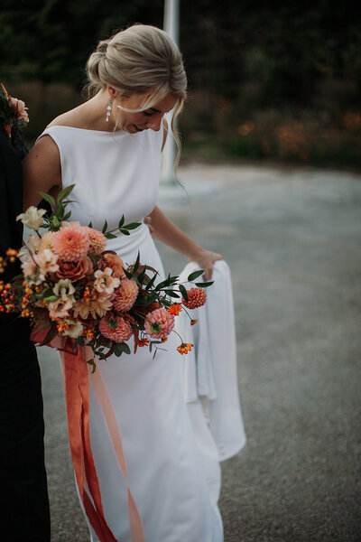 Blonde bride in elegant gown  with a large spring bouquet in hand