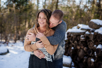 Jen and Mark Heller hugging with forest backdrop