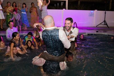 People playing in a pool in wedding clothes
