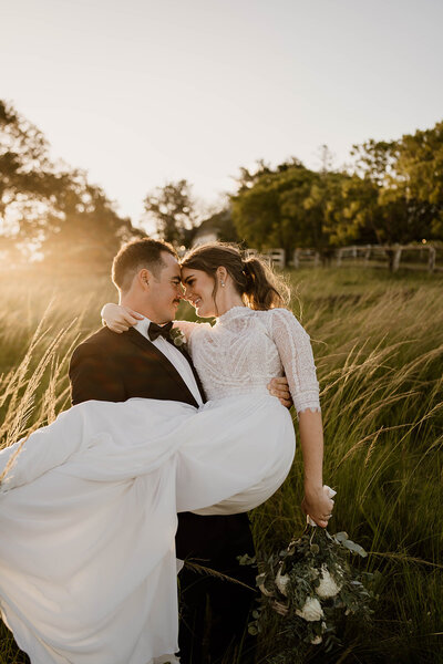 Groom picking up bride and enjoying an embrace at Albert River Wines - Mt Tamborine wedding