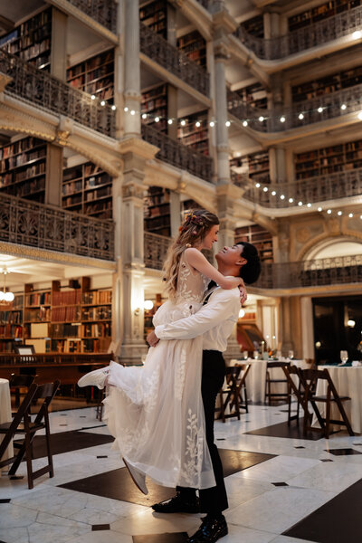Groom holding up his bride to spin her around on the dance floor of their reception. 