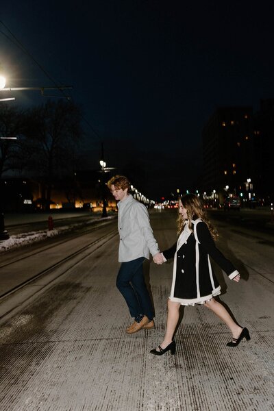 A couple holding hands and walking together across the street 