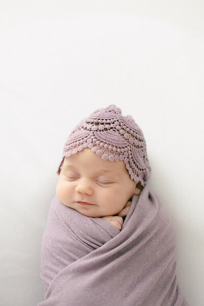 Baby in neutral pink wrap lying in a moses basket for a Tampa newborn photographer
