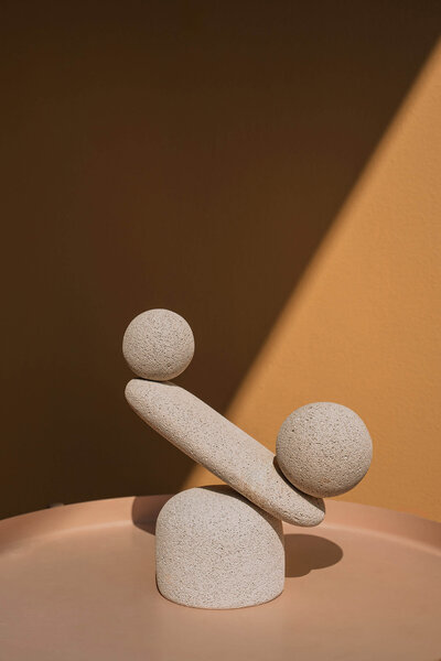Minimalistic image of a balanced stone stack against an orange backdrop, symbolizing harmony, balance, and mindfulness.