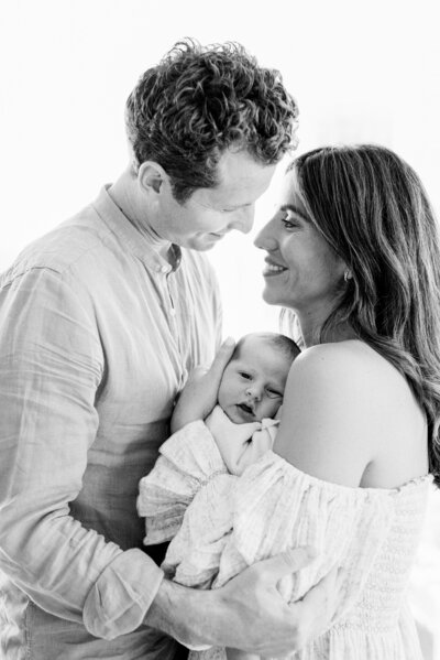 Black and white dad and mom holding newborn baby by Miami Newborn Photography
