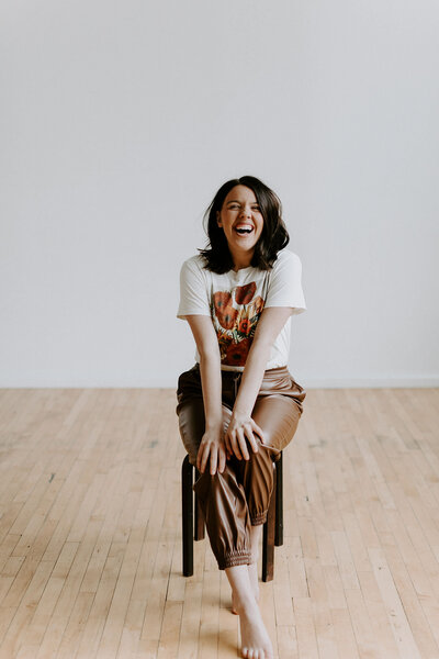 Whitley sitting on a stool and smiling at the camera