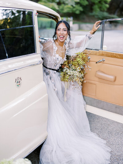 Bride laughing and dancing in a sparkling gown with groom in the background.