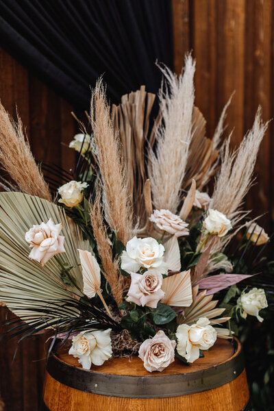 Boho inspired flower design with roses and pampas grass on a whiskey barrell