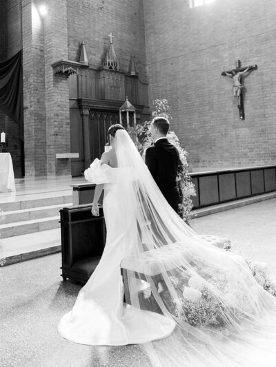 Bride and groom standing at the altar during their wedding ceremony in church. In black and white.