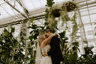 A wedding couple hugging each other in a greenhouse