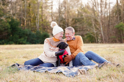 couple in field with  puppy