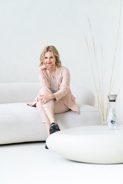 žena sedí na světlé pohovce a usmívá se