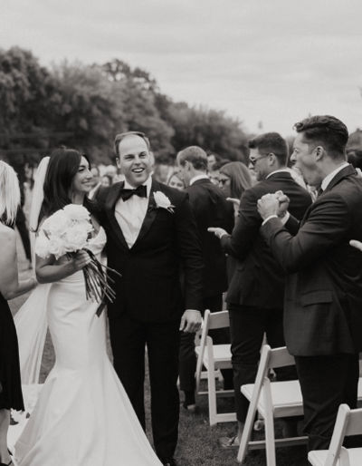 A bride and groom walking down the aisle seeing family and friends after just getting married