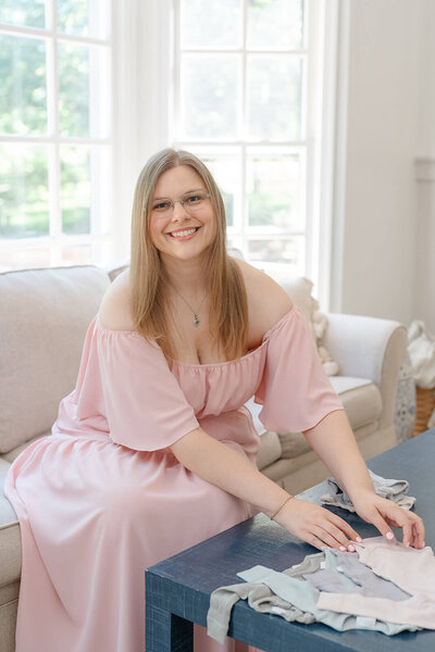 Northern Virginia photographer, Melissa Driggers, sitting at a desk working on her laptop and smiling at the camera.