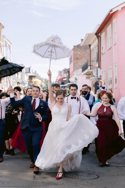 Bride and groom holding umbrellas during their second line parade through the French Quarter
