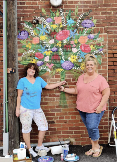 two women with mural of floral bouquet