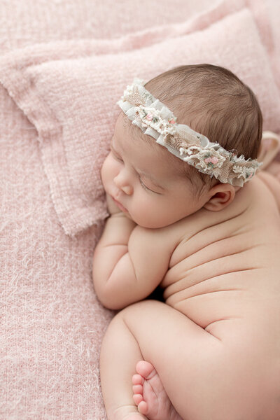 A posed baby sleeping during her in studio newborn photo session.