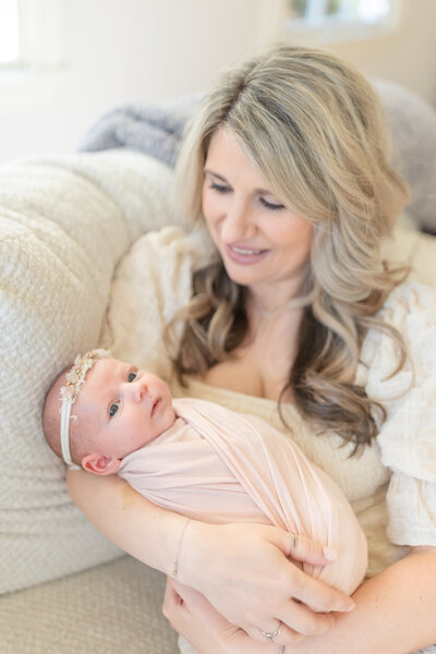 In-home lifestyle newborn session by Oak and Lore Studio, where a mother leans over her newborn baby in a crib in the nursery. The mother looks at her baby with love and tenderness, capturing a quiet, intimate moment in a beautifully styled nursery
