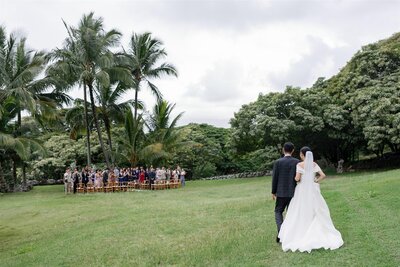 A person walking their child down the aisle during an outdoor wedding ceremony 