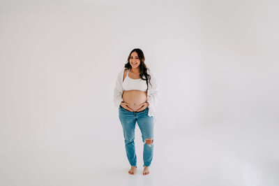 Springfield MO maternity photographer Jessica Kennedy of The XO Photographer captures pregnant mom in jeans laughing in studio