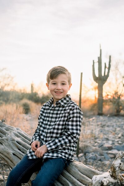 little boy sitting on the cactus smiling at the camera