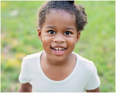 An enchanting child portrait session, capturing a little girls genuine expressions and emotions. The little girl is smiling and looking at the camera.