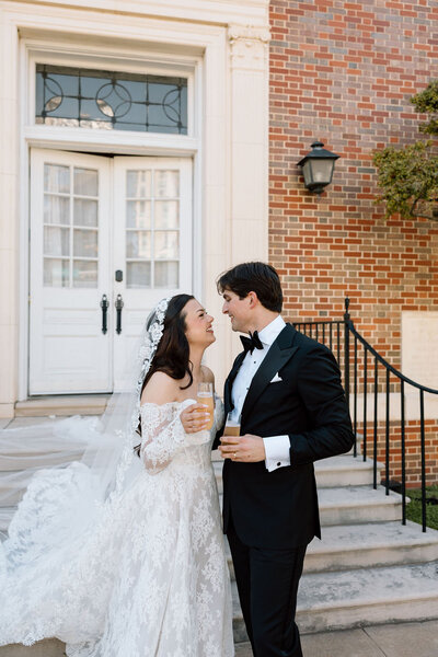 Bride and groom smiling with drinks on outdoor steps
