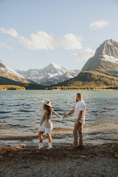Couple adventuring in Glacier National Park with mountain and lake views in the background.