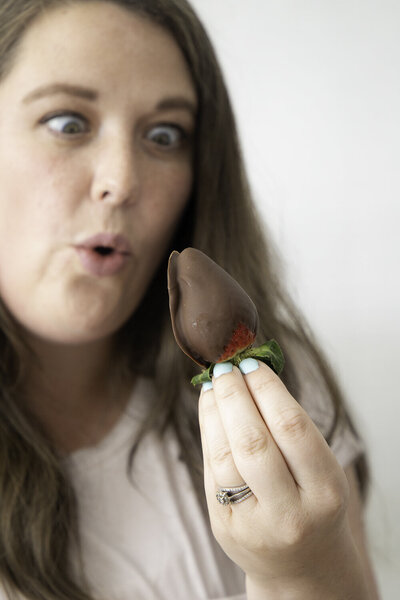 Allen Newborn Photographer looking at strawberry.