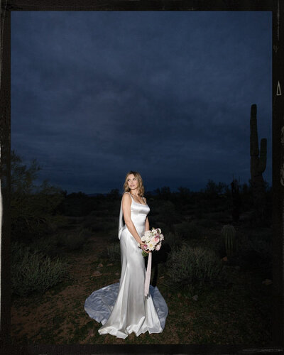 Bride in wedding dress standing in desert at night