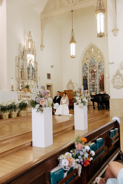 Elegant church wedding ceremony with floral arrangements lining the aisle and altar, designed by Yours Truly, a wedding planner and designer in New Jersey