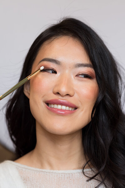 Smiling bride during makeup application at ODARA studio