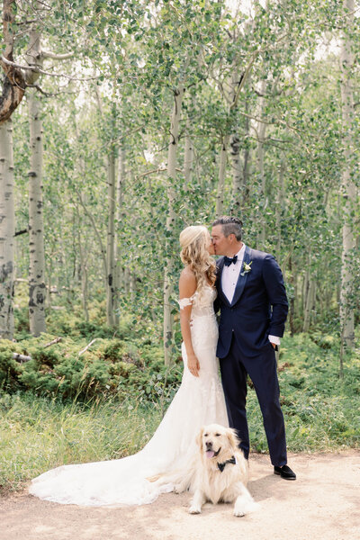 bride and groom kiss posed with dog