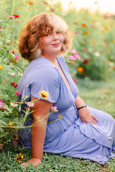 A high school senior wearing a purple dress sits in a wildflower field in Chesapeake, Virginia. Photo by Justine Renee Photography.
