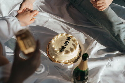 couple sharing cake and champagne during engagement photos, captured by Elsie Goodman, an NYC engagement and couples photographer