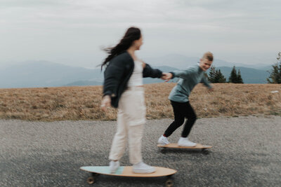 couple skateboarding on mountain road