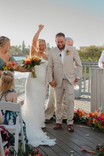bridge and groom holding hands walking down aisle in hawaii