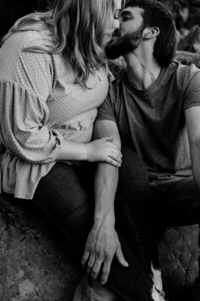 Engagement couple kissing in the woods.