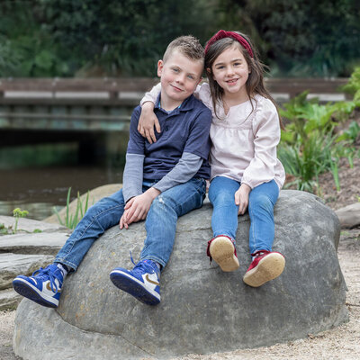 siblings sitting on a rock together
