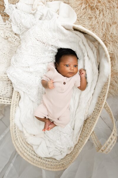 Newborn photography baby laying in basket on white blanket with boho background in Tampa Bay, Florida Nadine B Photography