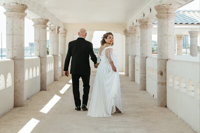 Groom walking away while holding bride's hand, and she is look back over her shoulder at Art Center in Corpus Christi, TX