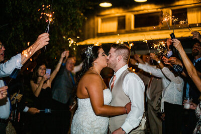 Bride and groom kiss during sparkler exit at Port Farms wedding reception