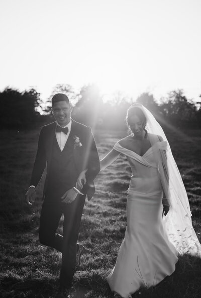 Bride and groom laughing  and walking at dewsall court