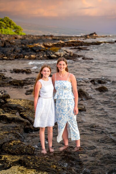 Two girls standing on lava rock for hawaiian family photoshoot
