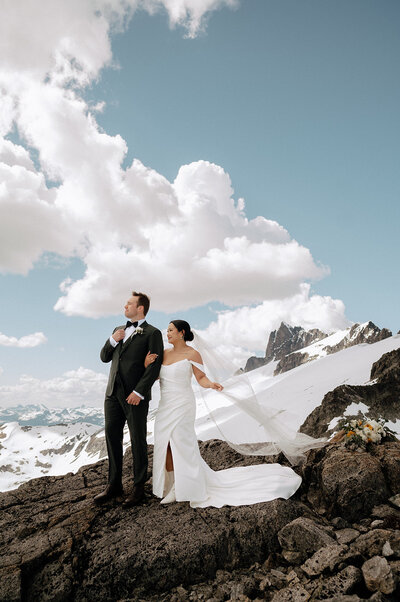 Helicopter elopement wedding in BC mountains with cloudy and blue sky